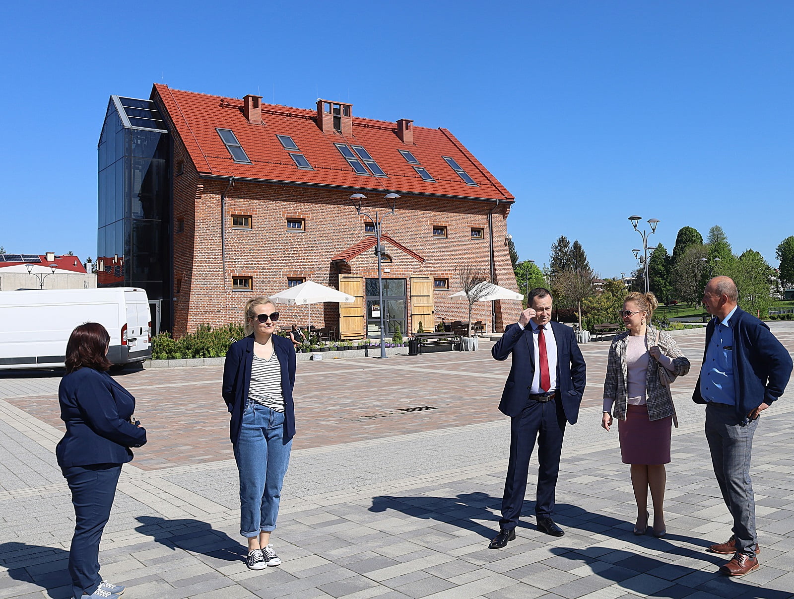 pięć osób stojących przed budynkiem z czerwonej cegły